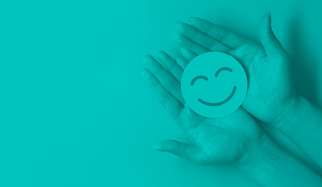 hands holding a circle with a smiling face drawn on it representing happy employees at a company