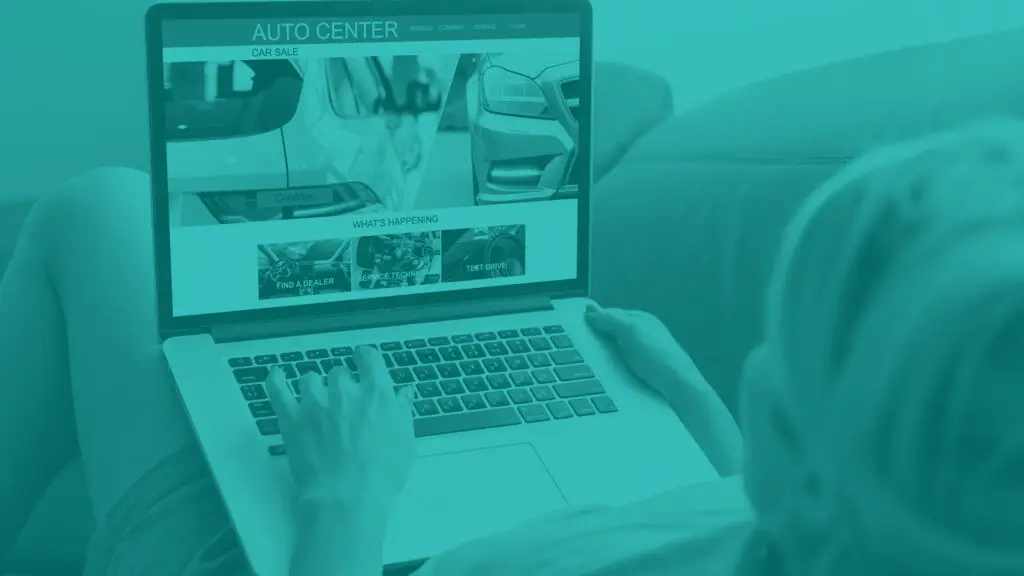 Woman with laptop shopping on an automotive website which is displayed on the laptop screen.