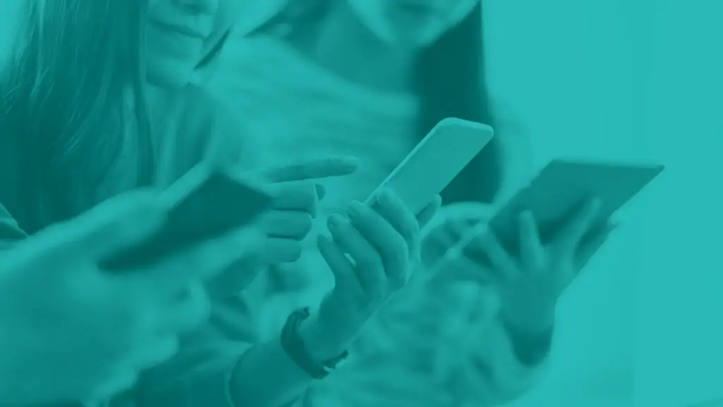Close up of smart phones held by a group of young people looking at phones one wonam reaching to touch her phone screen.